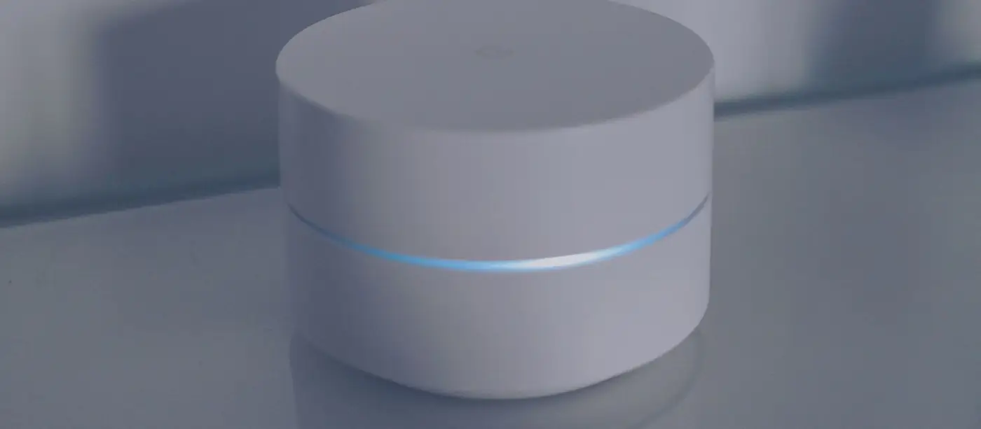 A white smart home hub device with a blue light ring on a reflective surface